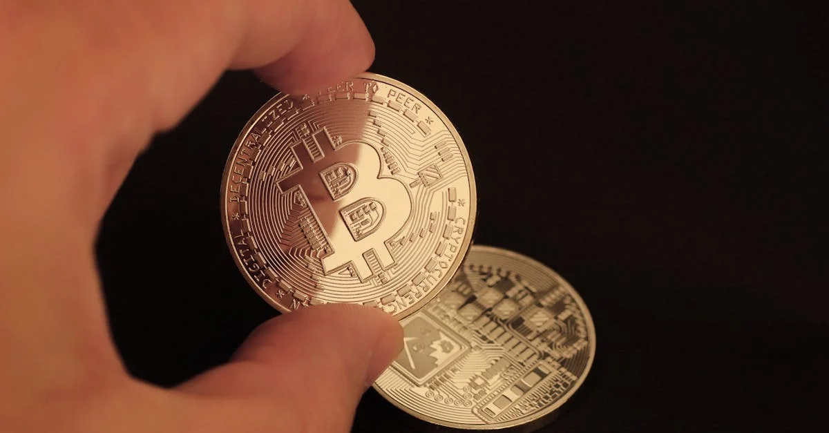 Close-up of a hand holding a Bitcoin coin on a dark background.