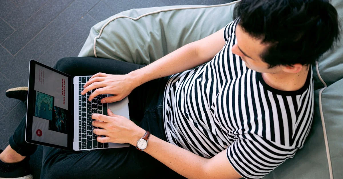 A man in a striped shirt using a laptop on a bean bag, embodying relaxed productivity.