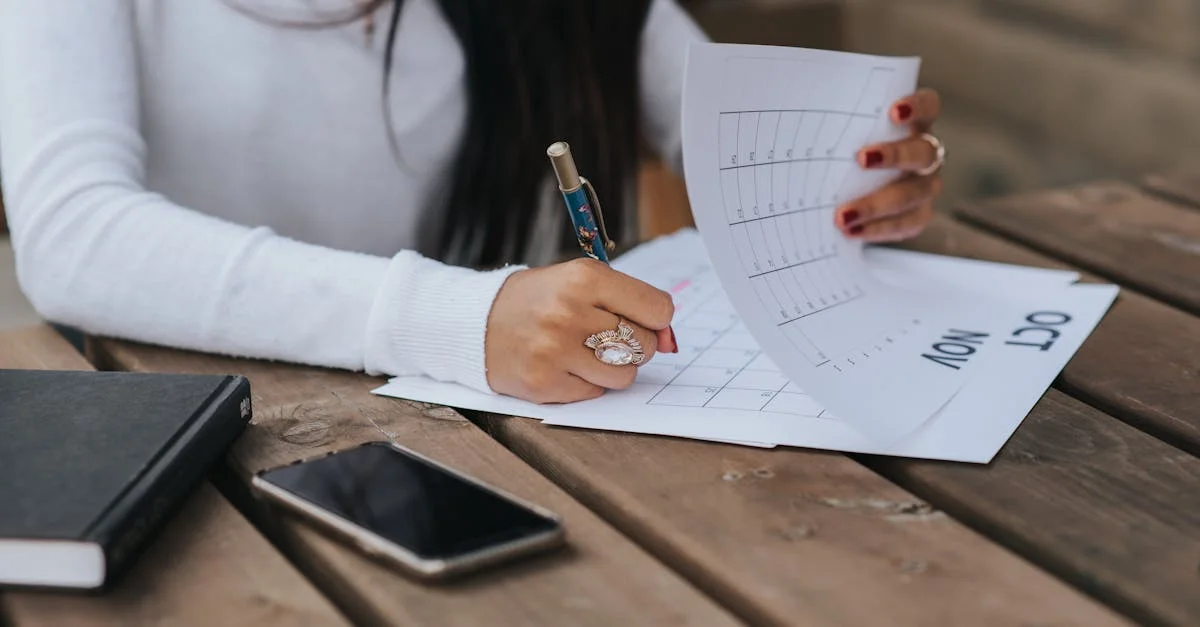 A woman writing in a calendar and notebook on a wooden table outdoors.