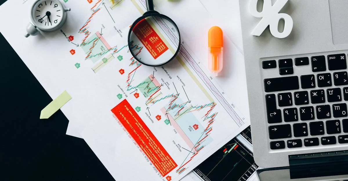 Top view of financial documents, charts, and laptop organized on a desk.