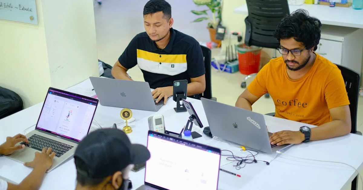 Team of Asian men working collaboratively in a modern office setting with laptops.