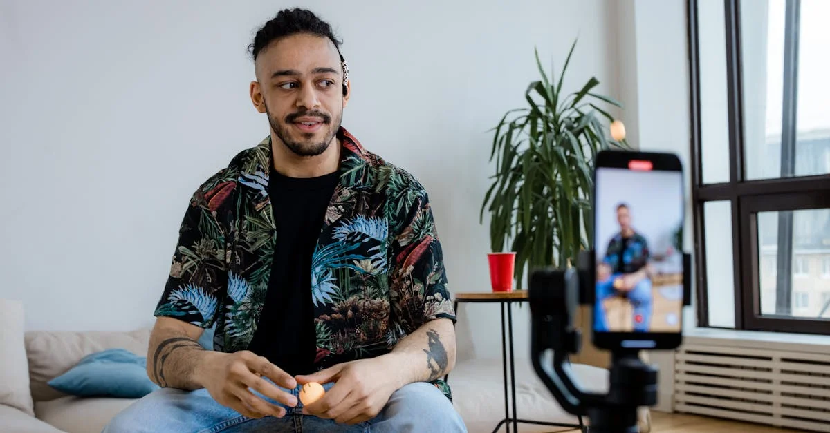 A young man recording video content indoors with a smartphone and tripod.